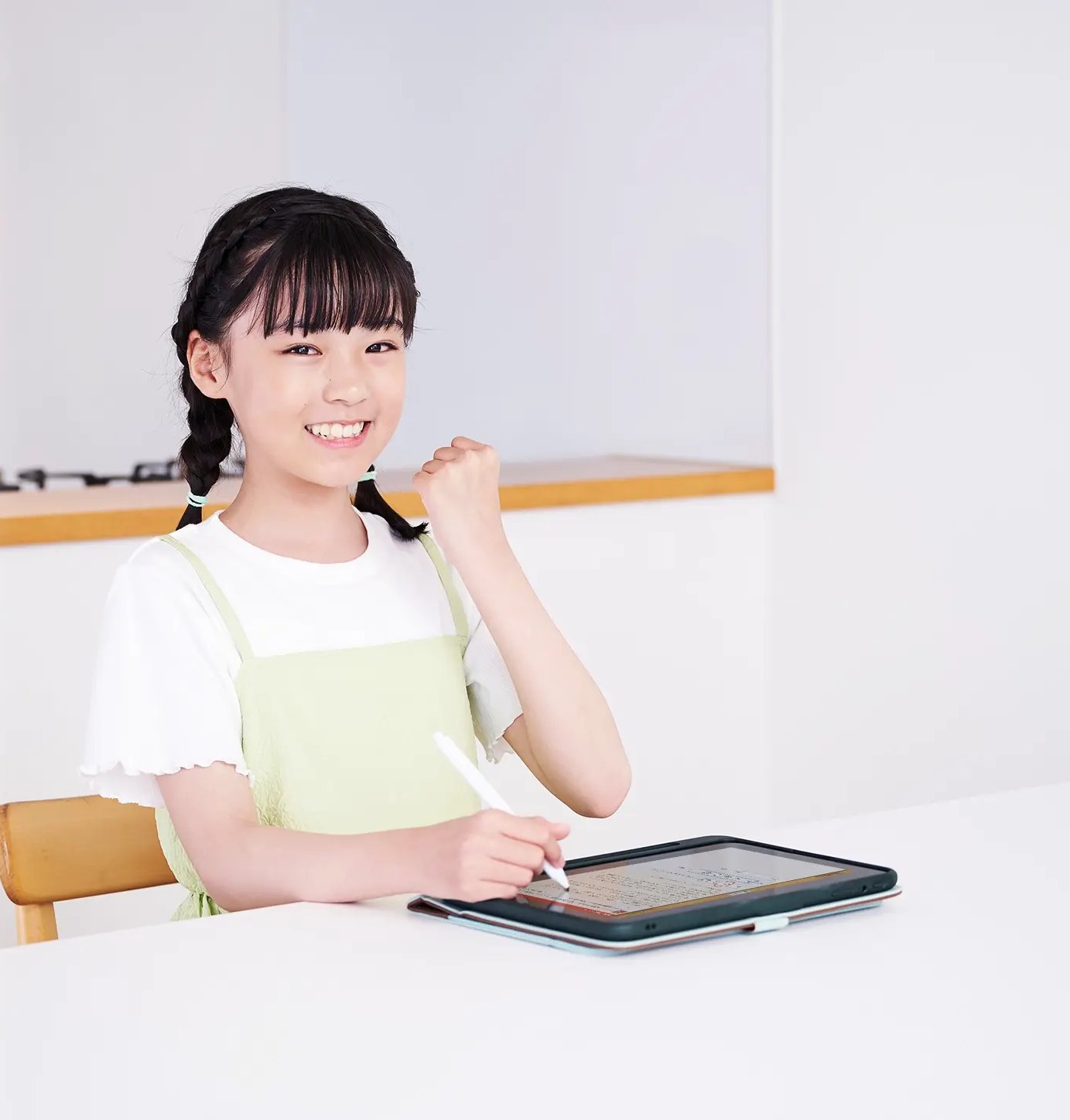 スマイルゼミで学ぶ家庭のイメージ。リビングで専用タブレットに向かって一人で学習する小学生の女の子